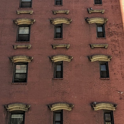 A brick building facade with multiple windows, each having decorative stone accents above them.