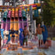 Four people holding mats walk through shallow water at the end of colorful water slides in an outdoor water park.