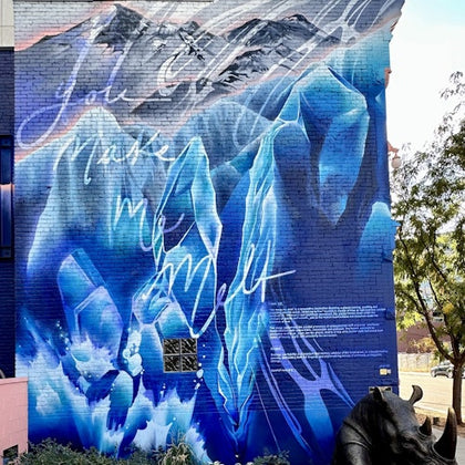 A vibrant mural on a brick wall featuring blue ice formations and mountains, with text integrated into the design.