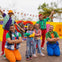 A group of six people, including two children and four adults, posing cheerfully in colorful outfits outdoors.