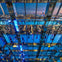 A mirrored interior reflecting people, city lights, and the skyline, including the Empire State Building at dusk.
