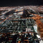 Aerial nighttime view of a cityscape with illuminated streets, buildings, and highways.