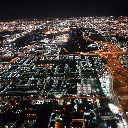 Aerial nighttime view of a cityscape with illuminated streets, buildings, and highways.