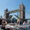 People on a boat viewing Tower Bridge in London, with its bascules raised and the city skyline in the background.