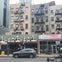 Street scene with buildings featuring fire escapes, a mural, parked car, and a motorcycle passing by.