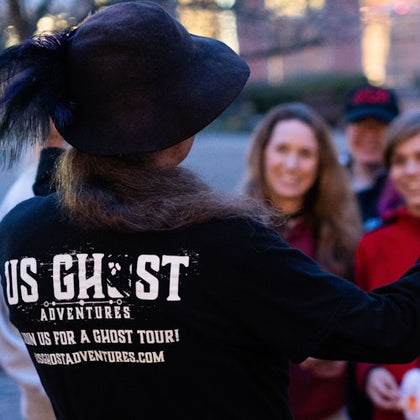 Tour guide making a tour group laugh while holding their EMF detectors, picking up on a paranormal activity