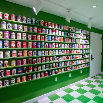 A wall with shelves displaying an assortment of colorful cans in a room with green and white checkered flooring.