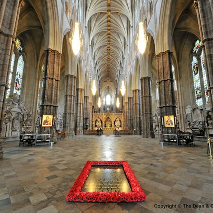 Gothic cathedral interior with vaulted ceilings, grand columns, ornate stained glass, and a decorated plaque on the floor.
