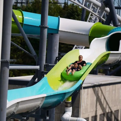 People sliding down a colorful water slide at an outdoor water park on a sunny day.