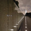 A reflective wall with engraved names, illuminated by ground lights, leading to the Washington Monument at night.