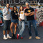 Four people in Hard Rock Cafe clothing pose in front of a wall with colorful graffiti.