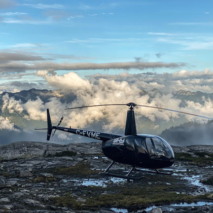 A helicopter landed on a mountain with mountain views in the background.