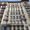 A multi-story historic building facade with ornate details, arched windows, and decorative stone carvings under a blue sky.