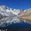 A tranquil mountain lake reflecting snow-covered peaks under a clear blue sky.