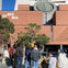 A group of people standing outside the SFMOMA building, characterized by its red brick facade, trees, and modern architectural elements.