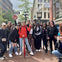 A group of people posing for a photo on a cobblestone street near a steam clock and a stop sign in an urban area.