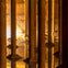 A view of tall columns reflected in water within an illuminated underground structure with stairs visible in the background.