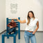 A woman poses in front of a large blue chair with a man sitting on it, creating an optical illusion at the Museum of Illusions Denver.