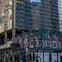 A city building with a restaurant at the base displaying American flags and surrounded by reflective glass structures.