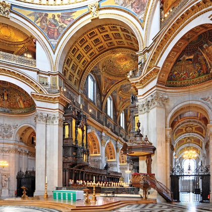Interior of a grand cathedral with ornate arches, detailed frescoes, and a central altar with lit candles.