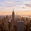 View of a cityscape with the Empire State Building prominently featured during sunset.