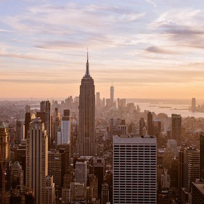 View of a cityscape with the Empire State Building prominently featured during sunset.