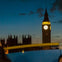 Big Ben and the Houses of Parliament at dusk with a blue sky and a blurred foreground element.