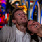 A man and a woman smiling and looking up, with colorful stained glass windows in the background.