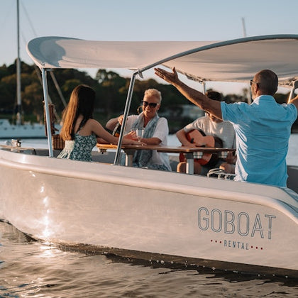 A GoBoat sailing with four guests onboard sharing stories over a bottle of wine 