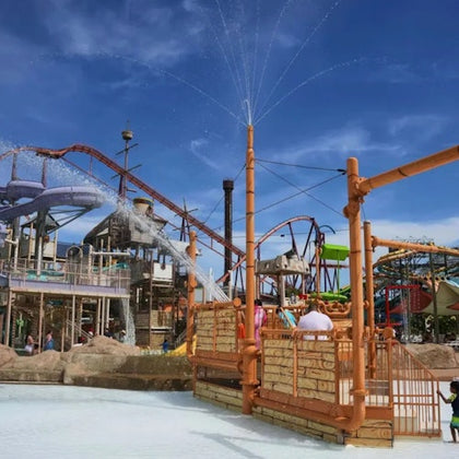 A water park with fountains, slides, and various attractions under a clear blue sky.