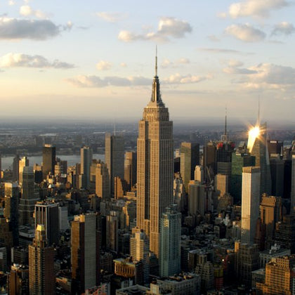 Aerial view of a city skyline with the Empire State Building prominently in the center and other skyscrapers surrounding it.