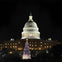The U.S. Capitol at night with a brightly lit Christmas tree in front, surrounded by people.