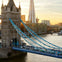 Tower Bridge in London with a view of the Shard and the Thames River at sunset.