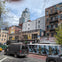 Urban street scene with graffiti-covered buildings, a black van and yellow taxi on the road, and trees in the foreground.