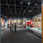 People view exhibits and information panels in a modern museum gallery with dark lighting and large, graphic displays.