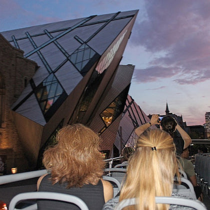 Open top double decker bus approaching the Royal Ontario Museum in the late evening