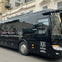Black tour bus for Evan Evans Tours, parked on a street in front of beige buildings, advertising London to Bicester Village route.