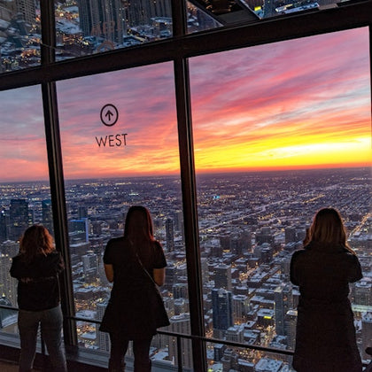tourists gazing at chicago cityscape below at the top of 360 Chicago observatory