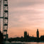 Ferris wheel pods on the left with the Houses of Parliament and Big Ben in silhouette against a sunset sky.