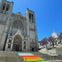 A large cathedral with gothic architecture, featuring rainbow-colored steps leading up to the entrance.