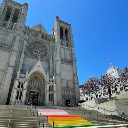 A large cathedral with gothic architecture, featuring rainbow-colored steps leading up to the entrance.