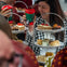 People enjoying an afternoon tea with tiered trays of cakes and sandwiches, holding festive red cups, smiling.