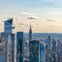 Aerial view of New York City skyscrapers, including the Empire State Building, under a partly cloudy sky.