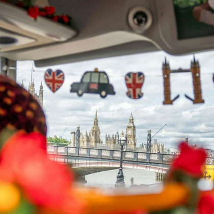 View of Big Ben and Westminster Bridge through a decorated vehicle window with British-themed ornaments.