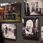 A wall displays five historical photos, including group portraits, scenes of destruction, and a man walking through ruins.