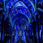 A cathedral interior illuminated with blue light projections resembling constellations and stars on its arches and ceiling.