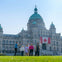 A group of people standing on a lawn in front of a historic building with a Canadian flag displayed.