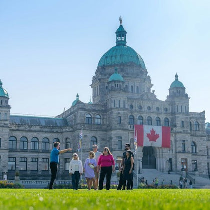 A group of people standing on a lawn in front of a historic building with a Canadian flag displayed.
