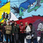 A group of people posing in front of a colorful graffiti wall featuring animated characters and vibrant designs.