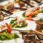 Plates of gourmet appetizers with shrimp, greens, and garnish, arranged neatly on a table.